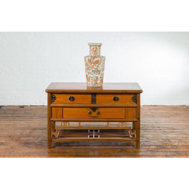 A Chinese sideboard from the early 20th century, with natural finish, three drawers and brass hardware. Created in China...