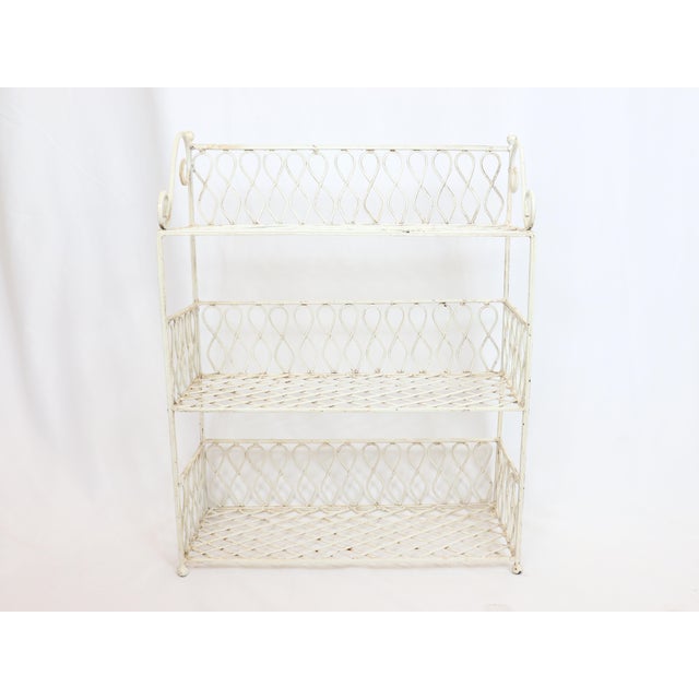 Vintage mid 20th Century iron shelving unit with three shelves. Figure 8 and scroll details with ball feet.