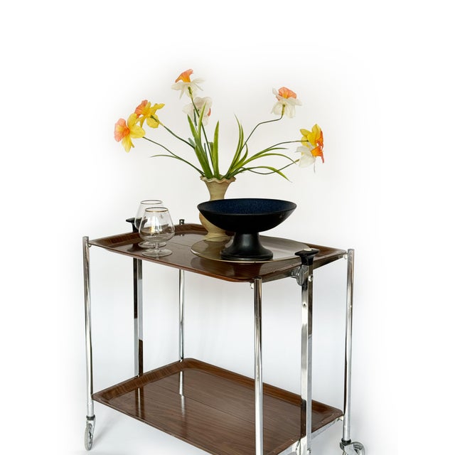 This elegant folding serving trolley from the 1970s features a minimalist design that combines a chrome-plated tubular...
