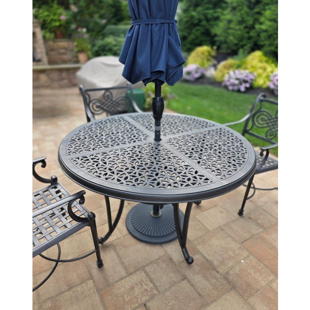 Like new - Outdoor dining set in wrought iron includes a round table and 4 arm chairs in a deep gray finish. Chair...