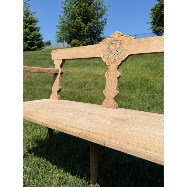 Mid 20th Century Swiss bench featuring a beautifully carved crest detailing and a softly weathered oak finish. A chariming...