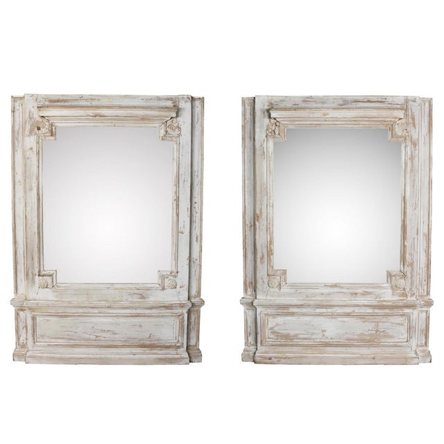 A striking pair of oversized painted trumeau mirrors with beautifully distressed cream finishes and classical...