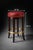A classic club-style bar stool featuring an oversized red leather swivel seat, richly finished mahogany legs, and a...