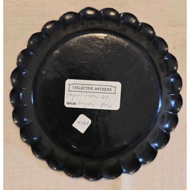 An antique 19th-Century English black lacquered papier mache plate or coaster peddled edges with hand painted gilt...