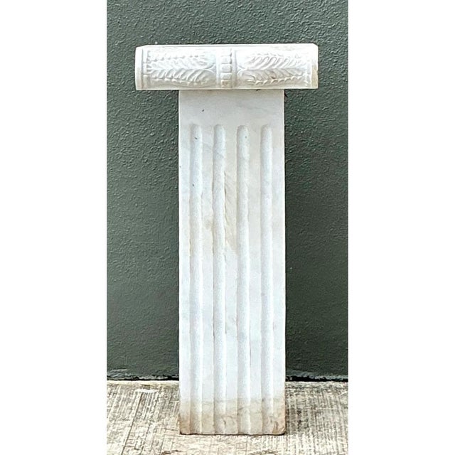 This vintage Ionic-style marble pedestal presents a stately, architectural silhouette, with a slender square shaft rising...