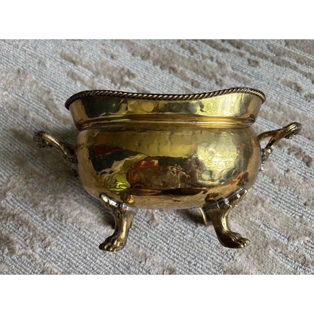 A diminutive hammered brass oval cachepot or jardiniere with solid brass carrying handles and solid brass paw feet, the...