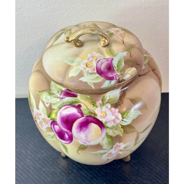 An exceptional example of early 20th-century Japanese porcelain, this Nippon biscuit jar features lush hand-painted plums,...