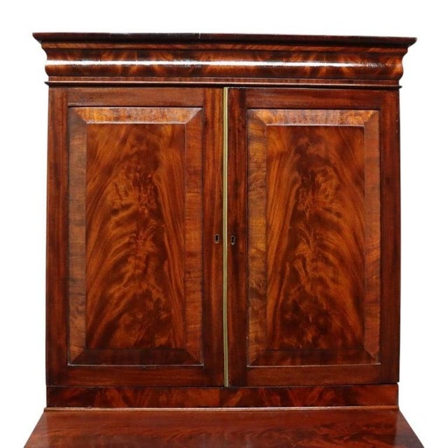 An antique American Empire Classical secretary desk, crafted circa 1840. This desk is constructed from flame mahogany,...