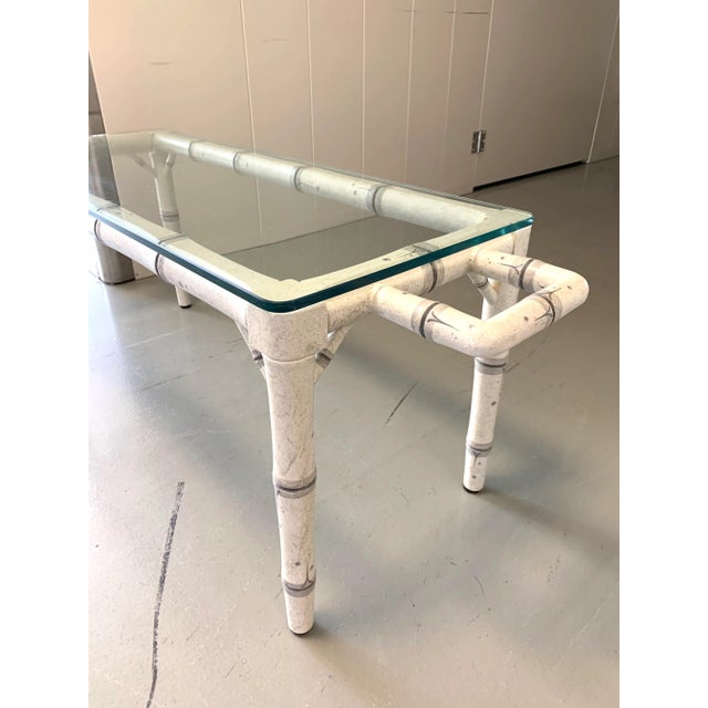 A mid-century, hand-painted coffee table with faux bamboo motif detailing with glass top and handles on opposing ends....
