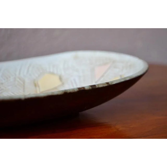 This pretty pocket or cup is made of ceramic. Oblong in shape, it is decorated with abstract geometric patterns in relief,...