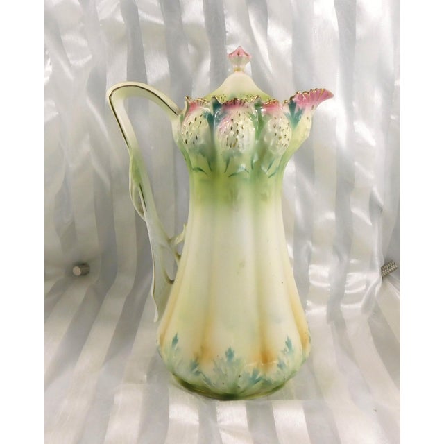This is an unmarked chocolate pot in green and pink with yellow. The top edge has a strawberry design and there is some...