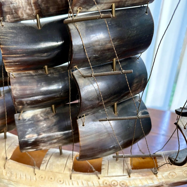 An exceptional vintage horn ship sculpture, handcrafted with layered, curved horn sails and mounted on a carved wooden...