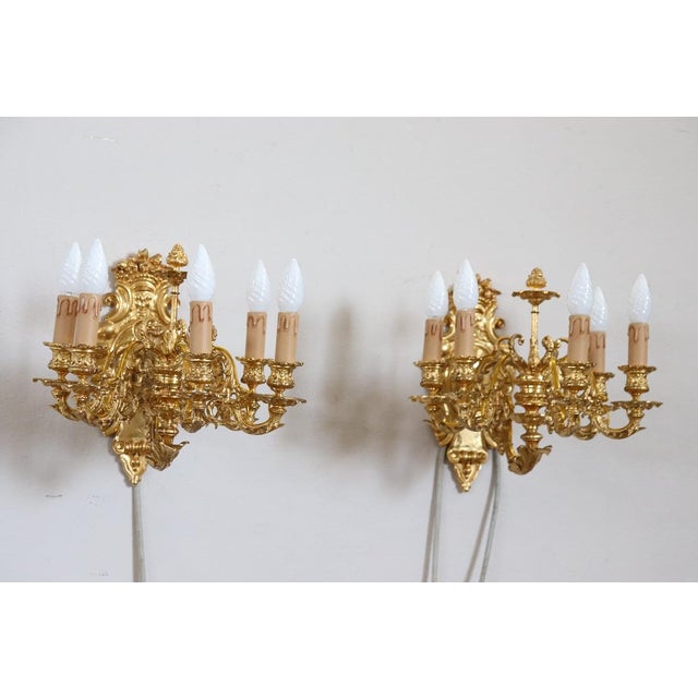Beautiful and refined 20th century, 1970s circa, pair of wall lights or sconces with five lights each. Made of gilded and...