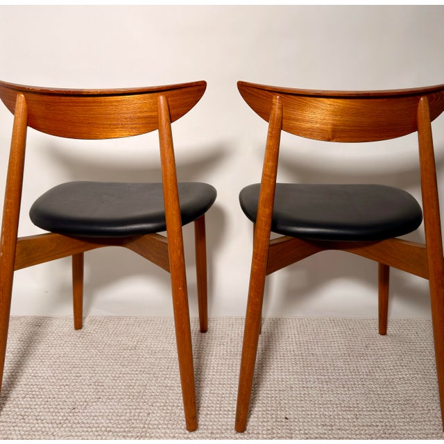 A handsome pair of Danish modern teak dining chairs dating to the mid-20th century. The chairs feature sculptural crescent...