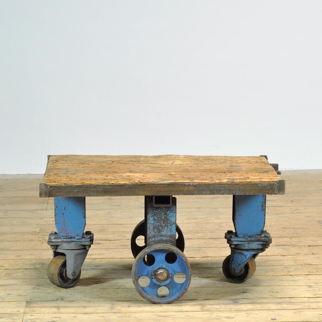 A 1960s industrial coffee table featuring a combination of a heavy wooden top and a robust metal base. The weathered wood...