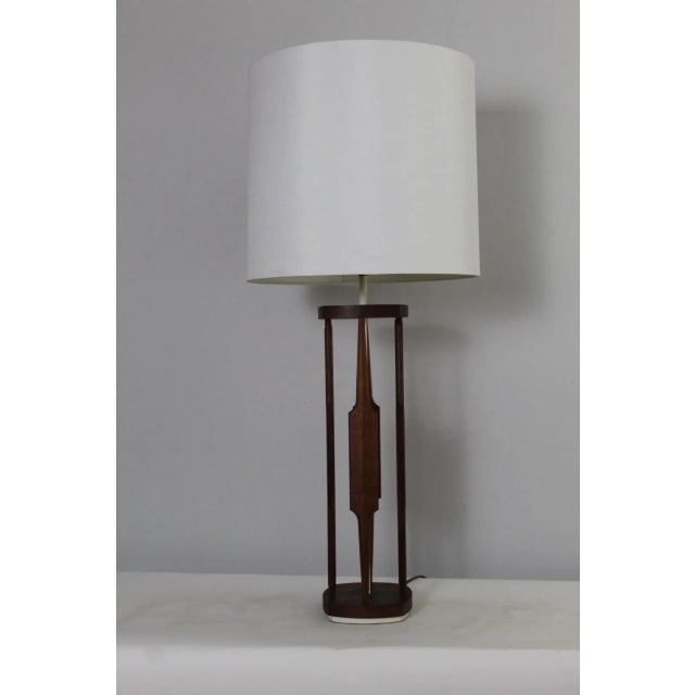 Sculptural table lamp. Beautiful hand rubbed walnut mounted on cast enameled alabaster colored base and stem. Helps to...