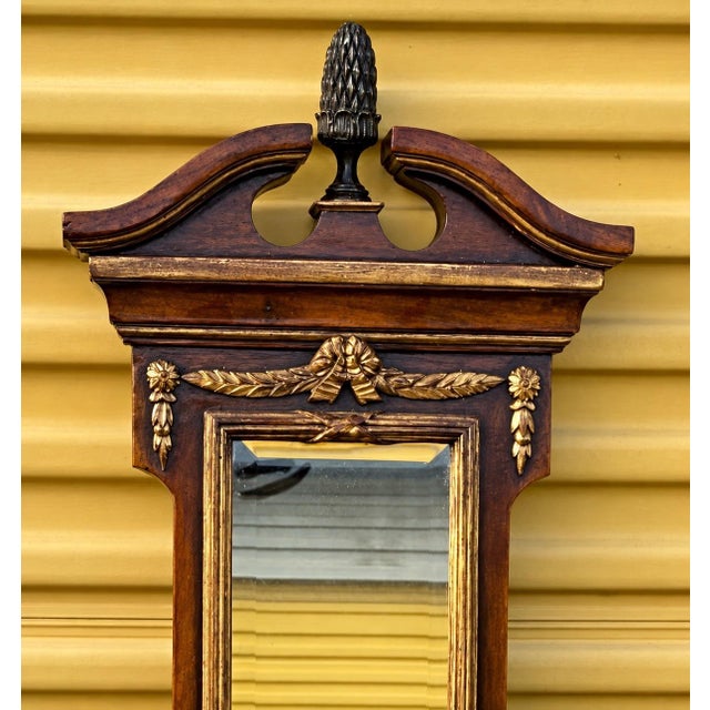 This is a Theodore Alexander 62 inch neoclassical style carved mahogany and gilt wall mirror with shelves and bracket....