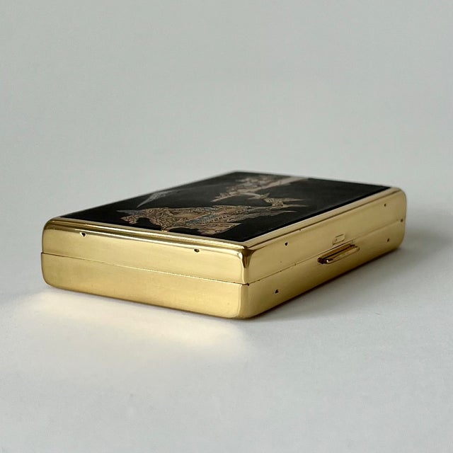 This rectangular vanity item functions as a combined powder compact and mechanical music box. The exterior features a...