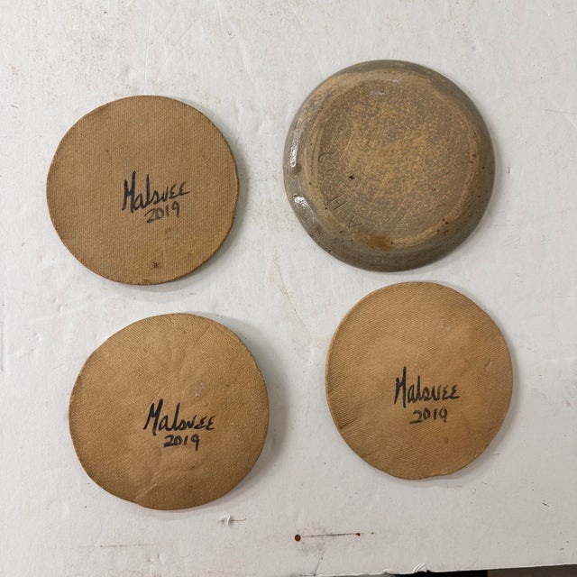 An assortment of art pottery handmade kitchen accessories such as coasters, spoon rest or trivets. Each features a...