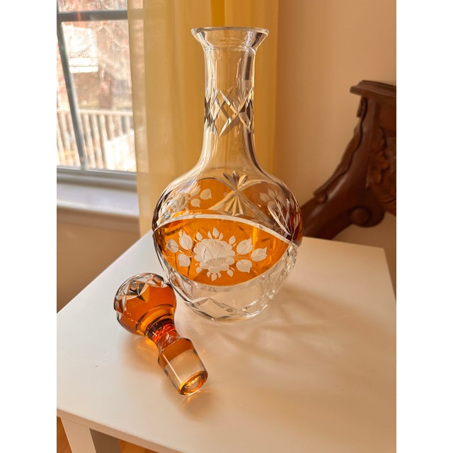 This item is a vintage Bohemian amber cut-to-clear crystal decanter with a floral pattern and a stopper. These pieces are...