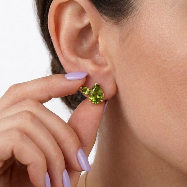 Elevate your collection with these vibrant three-stone peridot cluster earrings. This design features a prominent, pear-...