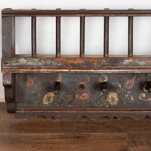 19th-century hanging rack crafted in pine with an original hand-painted finish. While it appears as black at first glance,...