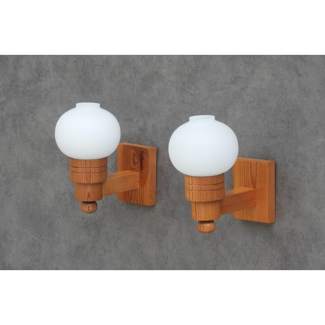 A charming pair of Swedish Modern wall sconces crafted in solid pine and fitted with nicely proportioned opaline glass...