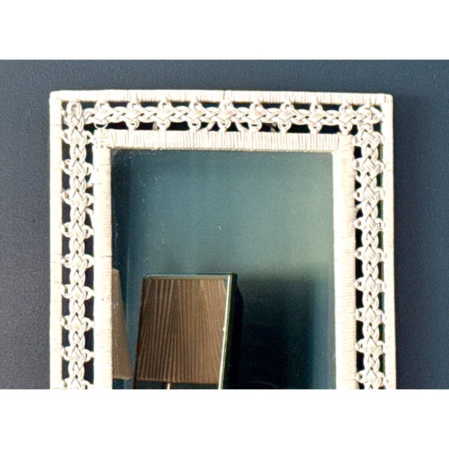 A beautifully detailed vintage white wicker mirror featuring an intricate braided frame and sculptural woven loops. The...