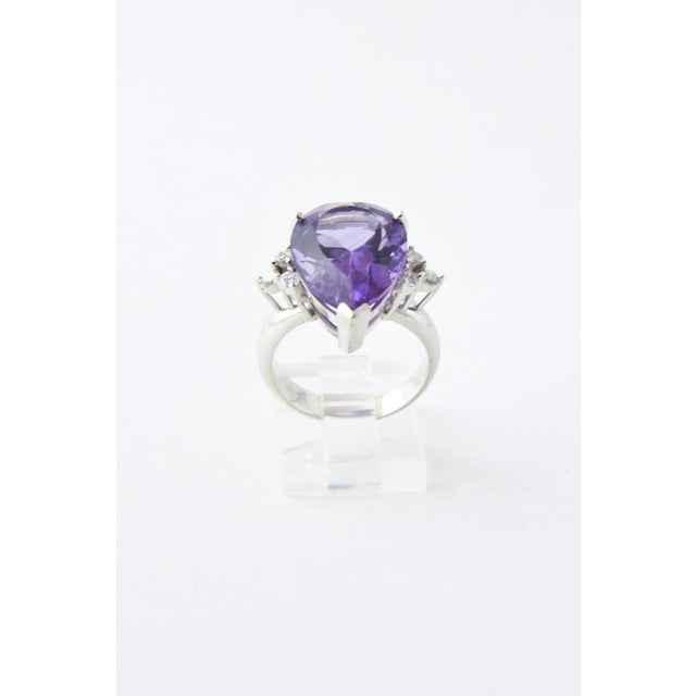 14K white gold ring presenting a faceted pear-shaped amethyst accented with three prong-set diamonds on each side....
