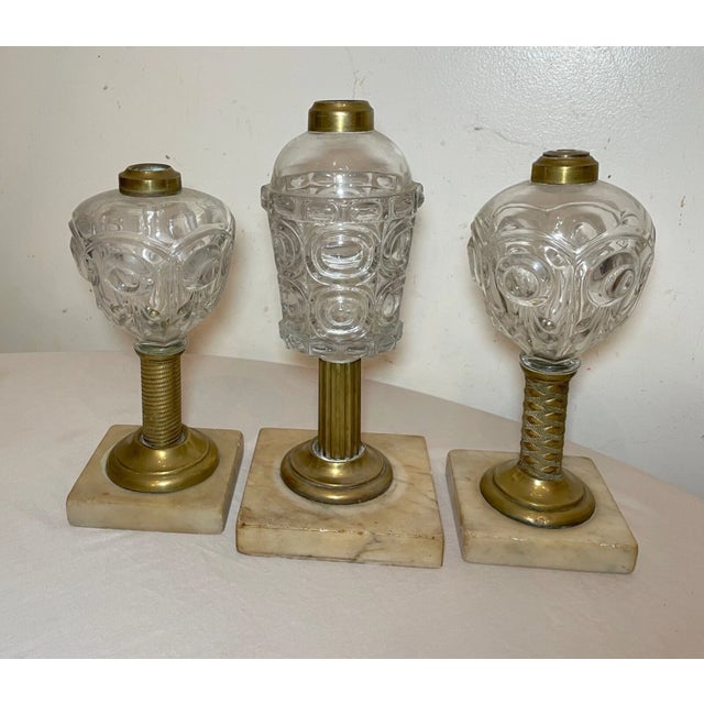 This lot includes three rare antique 19th century oil lamps with bullseye glass, brass, and marble accents. These lamps...