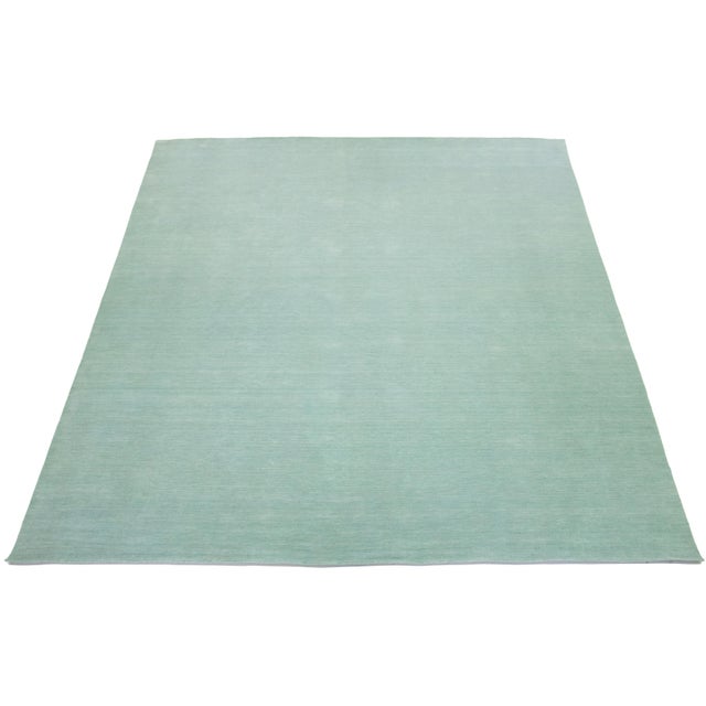 This handcrafted custom wool rug, designed in the Gabbeh style, features a solid light green design. It is part of our...