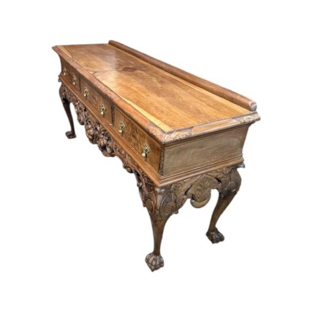 This is a really nice carved console table. Made from walnut and made in England. It has three drawers with brass lion-...