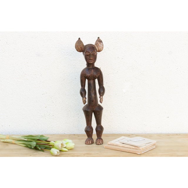 Some figures are carved to be looked at from one angle. This one rewards walking all the way around it. The face is quiet...