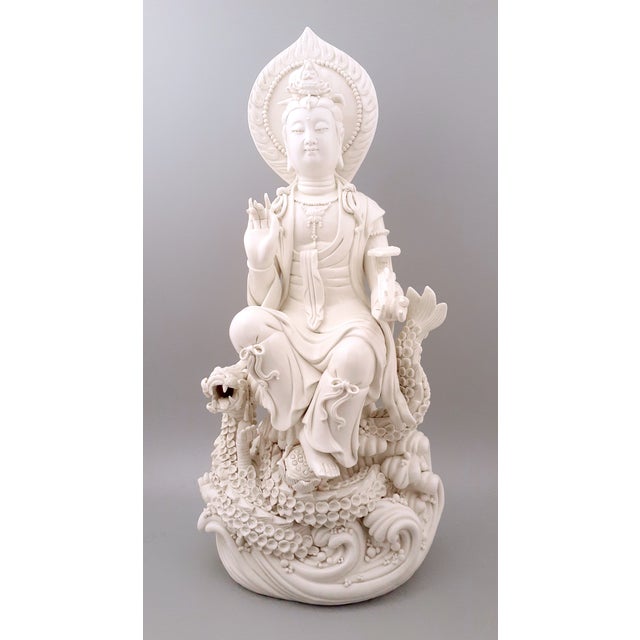 Chinese DeHua porcelain Kuan Yin seated on a dragon throne, formed by a coiled water dragon, amid roiling ocean waves,...