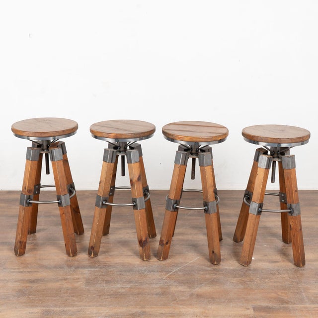 Set of four 20th century industrial barstools, crafted in pine with visible knots and natural wood grain throughout. Metal...