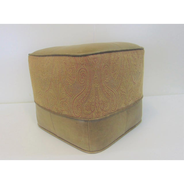Beige Leather Center tuft ottoman with a paisley print fabric band in the on the side with leather-trimmed base.