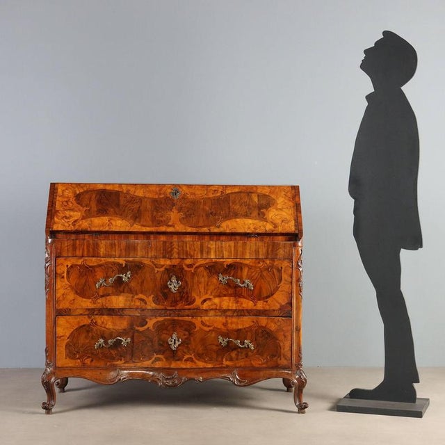 Walnut and walnut burl bureau, featuring curved frames inlaid with various woods, originating from Piacenza and dating...