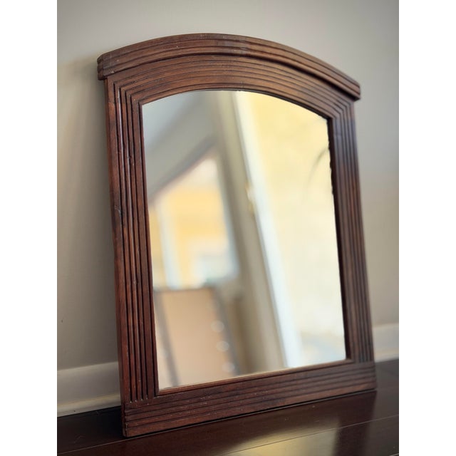 A handsome vintage arched mirror featuring a richly grained walnut finish frame with layered architectural molding and...