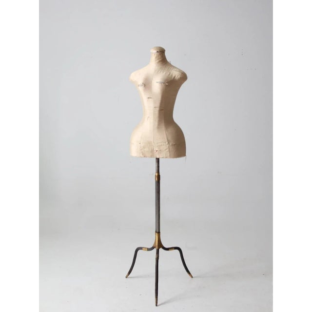This vintage dress form features a metal three footed stand with gold wire wrap accents, combined with a soft, distressed...