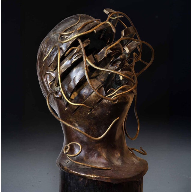 A striking sculpture by René Hetzel, depicting a fragmented male bust, pierced and encircled by an interlacing of bronze...