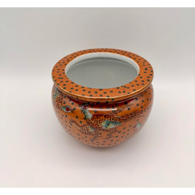 A charming vintage Chinese export porcelain cachepot featuring hand-painted pheasants against a warm terracotta-orange...