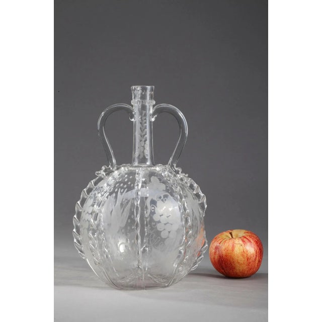 Glass Dutch jug with long neck and two handles. It is decorated with glass ribbons worked with pliers and with grape and...