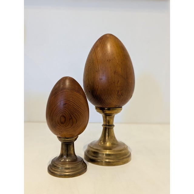 A graduated pair of decorative finial-form sculptures featuring lathe-turned hardwood ovoids mounted on substantial cast...