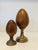 A graduated pair of decorative finial-form sculptures featuring lathe-turned hardwood ovoids mounted on substantial cast...