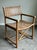 Handsome vintage coastal campaign-style armchair featuring a beautifully woven leather strap seat and back with faux...