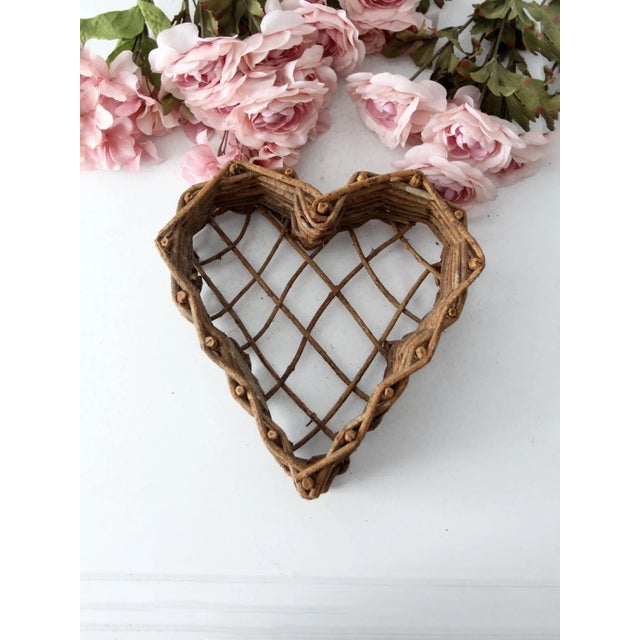 This is a vintage twig heart basket. Shaped as a heart, the open weave base cottage basket has a rustic twig frame with...