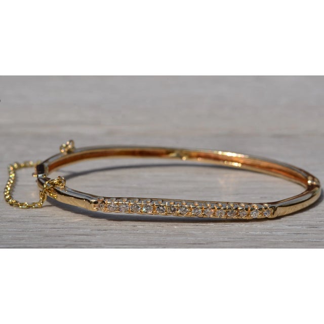 The Wasco: Contemporary Yellow Gold and Diamond Bangle Bracelet. The bracelet features a row of round brilliant cut...