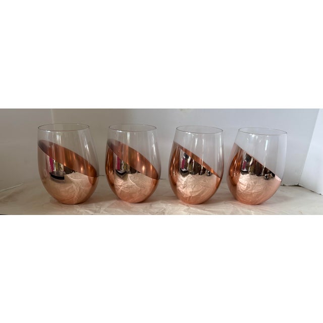 Elevate your entertaining with this sophisticated set of four contemporary stemless wine glasses featuring a striking rose...