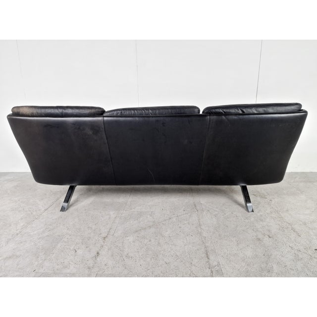 Mid-century three seater sofa designed by Carl Straub in black leather and teak. Beautifully shaped metal base. Good...