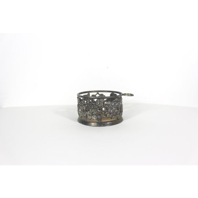 Vintage silver plated wine coaster with grape detailed sides, a loop to hold a cork or stopper and heavy patina and some...
